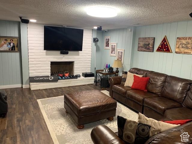 living room featuring a textured ceiling, a large fireplace, and dark hardwood / wood-style flooring