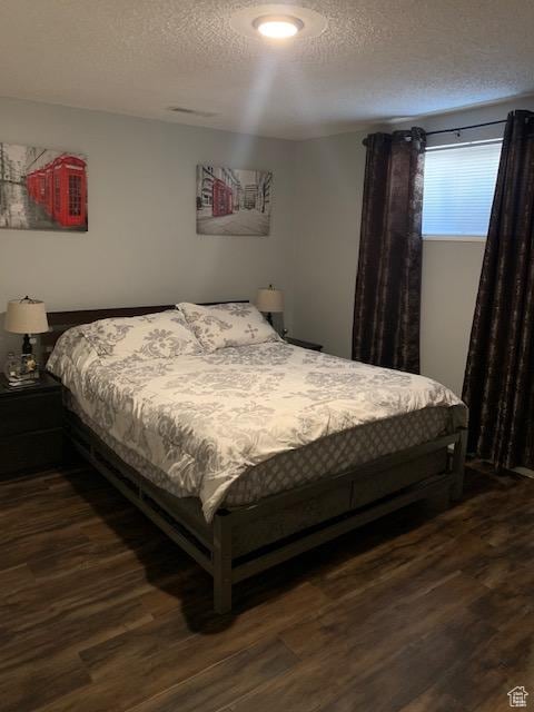 bedroom featuring dark hardwood / wood-style flooring and a textured ceiling