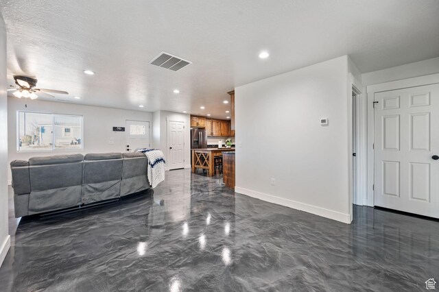 living room with ceiling fan and a textured ceiling