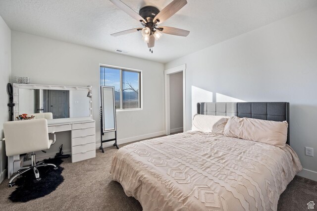 carpeted bedroom featuring ceiling fan and a textured ceiling