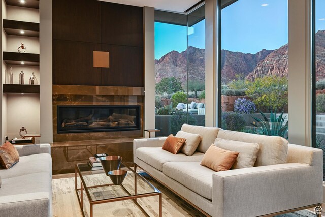 1748 N Cochise Dr, Ivins, UT 84738 - living area with floor to ceiling windows, wood finished floors, a mountain view, and a glass covered fireplace