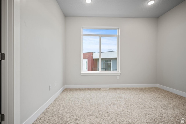 carpeted spare room featuring visible vents and baseboards