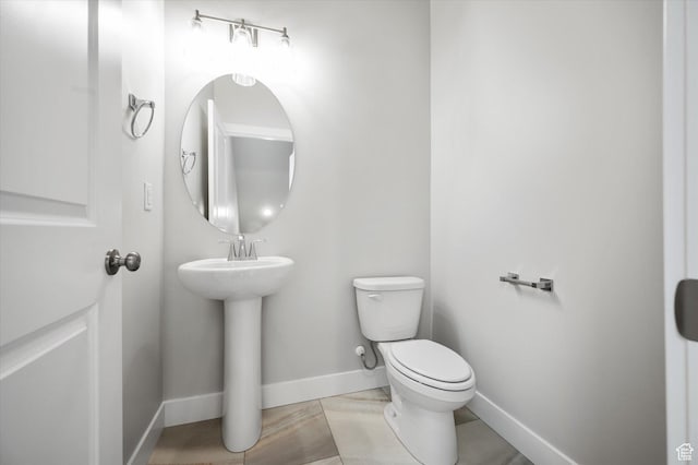 half bath featuring baseboards and toilet