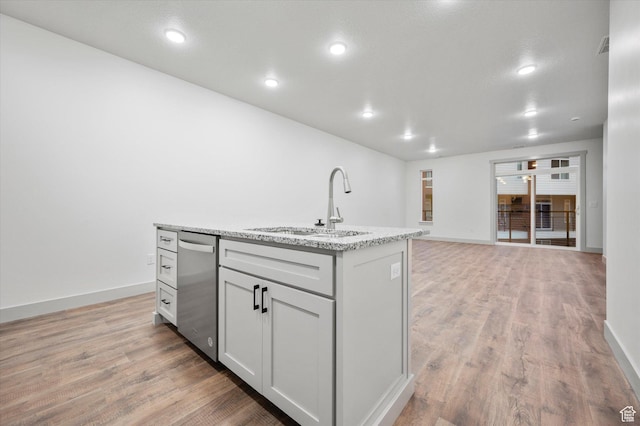 kitchen featuring light wood finished floors, baseboards, dishwasher, a kitchen island with sink, and a sink