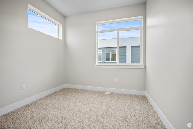 carpeted spare room featuring visible vents and baseboards