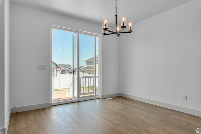 2523 N 3250 W, Clinton, UT 84015 - unfurnished room with light wood-type flooring, a textured ceiling, and an inviting chandelier