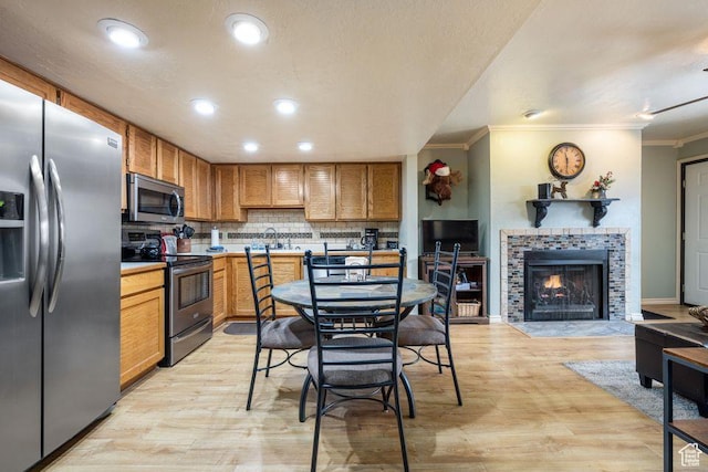 150 W Ridgeview St Unit 220, Brian Head, UT 84719 - kitchen with stainless steel appliances, ornamental molding, light wood-style flooring, tasteful backsplash, and a fireplace
