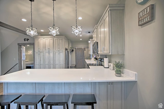 1400 N Cisco Cir, Garden City, UT 84028 - kitchen with appliances with stainless steel finishes, a peninsula, recessed lighting, light countertops, and a kitchen bar