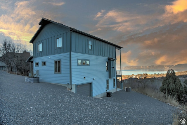 1400 N Cisco Cir, Garden City, UT 84028 - rear view of property featuring board and batten siding, a water view, an attached garage, central AC unit, and driveway