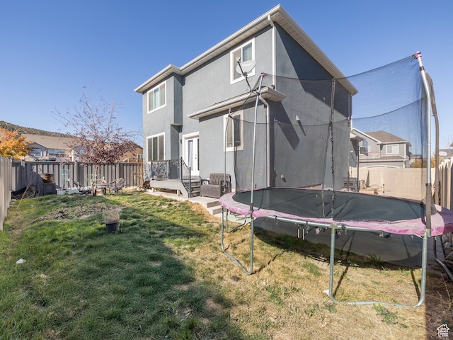 4182 E Paddock Way, Eagle Mountain, UT 84005 - rear view of house featuring a lawn and a trampoline
