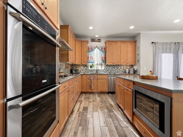 4182 E Paddock Way, Eagle Mountain, UT 84005 - kitchen with ventilation hood, stainless steel appliances, sink, decorative backsplash, and light hardwood / wood-style flooring