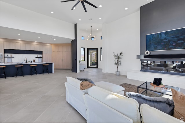 3967 N Hillside Way, Santa Clara, UT 84765 - living room featuring light tile patterned floors, a high ceiling, ceiling fan with notable chandelier, and sink