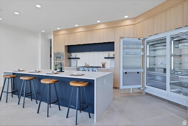 3967 N Hillside Way, Santa Clara, UT 84765 - kitchen with modern cabinets, a breakfast bar area, light countertops, light tile patterned flooring, and light brown cabinetry