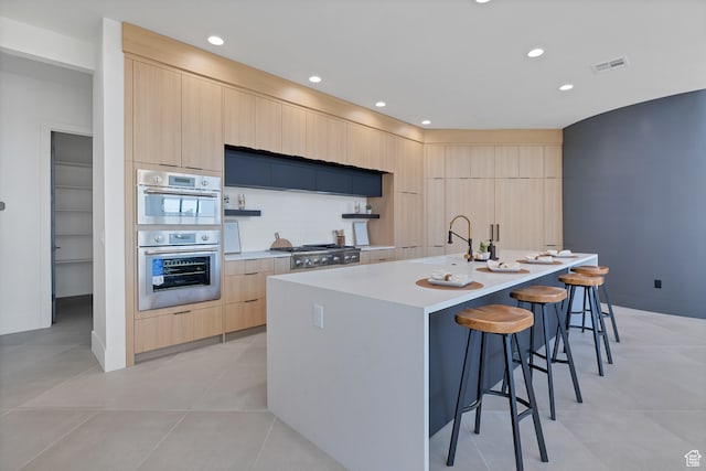 3967 N Hillside Way, Santa Clara, UT 84765 - kitchen featuring a center island with sink, appliances with stainless steel finishes, light brown cabinetry, a kitchen bar, and light tile patterned floors