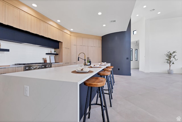 3967 N Hillside Way, Santa Clara, UT 84765 - kitchen with sink, stainless steel range, a kitchen breakfast bar, light brown cabinets, and a large island with sink