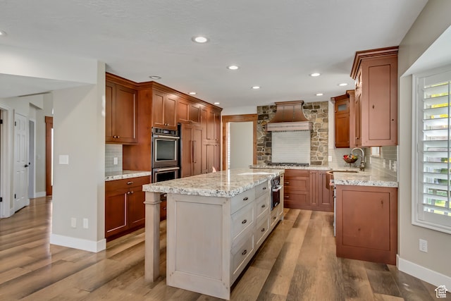 158 E Shepard Ln, Kaysville, UT 84037 - kitchen featuring custom exhaust hood, light wood-type flooring, light stone countertops, tasteful backsplash, and a kitchen island