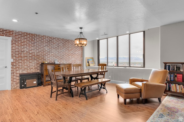 44 W Broadway S Unit 1205S, Salt Lake City, UT 84101 - dining space featuring an inviting chandelier, a textured ceiling, brick wall, and light wood-type flooring