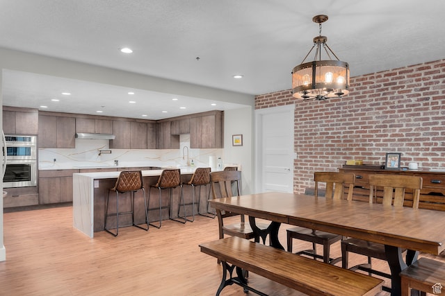 44 W Broadway S Unit 1205S, Salt Lake City, UT 84101 - dining area featuring sink, light wood-type flooring, an inviting chandelier, and brick wall