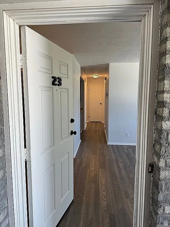 hall with dark wood-type flooring and a textured ceiling