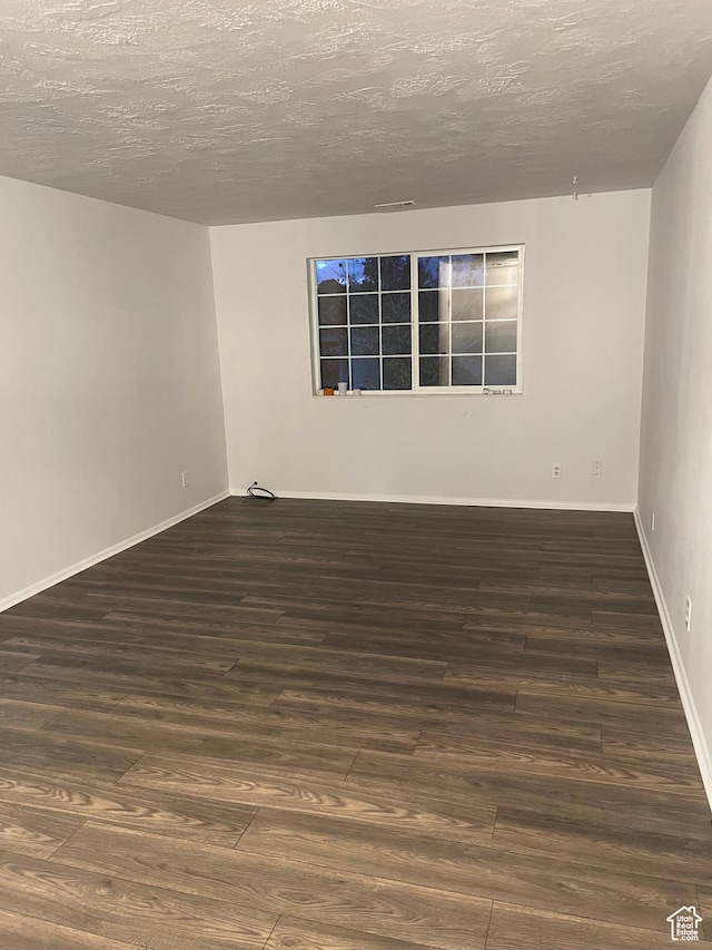 empty room with a textured ceiling and dark hardwood / wood-style floors