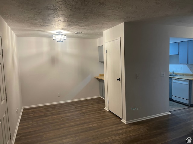 unfurnished dining area with dark hardwood / wood-style flooring, sink, and a textured ceiling