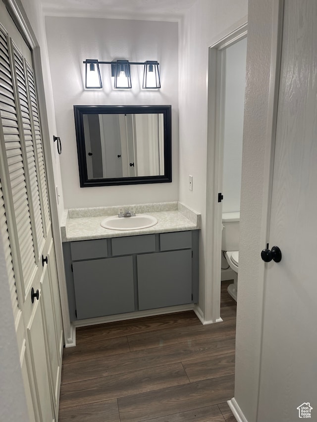 bathroom featuring wood-type flooring, vanity, and toilet