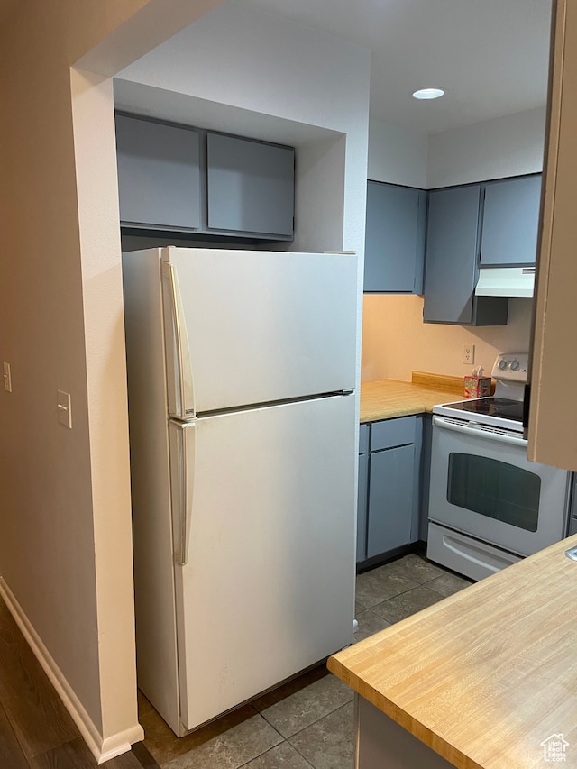 kitchen with white appliances, tile patterned flooring, and exhaust hood
