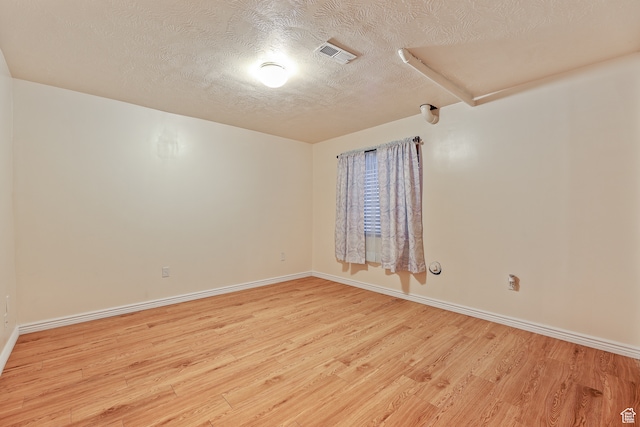 spare room with light hardwood / wood-style floors and a textured ceiling