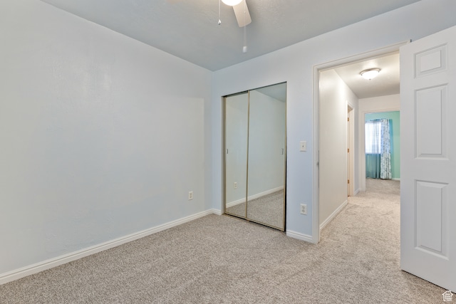 unfurnished bedroom featuring light carpet, ceiling fan, and a closet