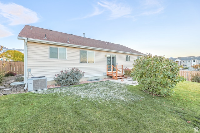 back of property with a lawn and central AC