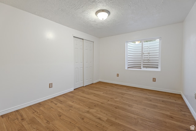 unfurnished bedroom featuring a closet, a textured ceiling, and light hardwood / wood-style flooring