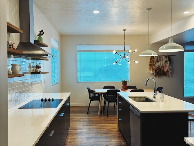 kitchen with sink, tasteful backsplash, stainless steel dishwasher, wall chimney range hood, and decorative light fixtures