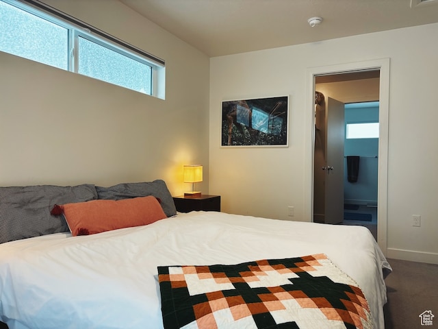 bedroom with ensuite bathroom and carpet floors