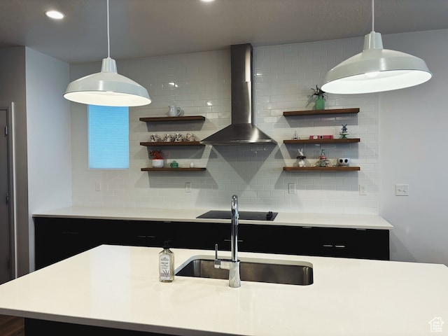 kitchen with sink, wall chimney exhaust hood, decorative light fixtures, black electric stovetop, and decorative backsplash