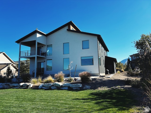 back of property with a lawn and a balcony