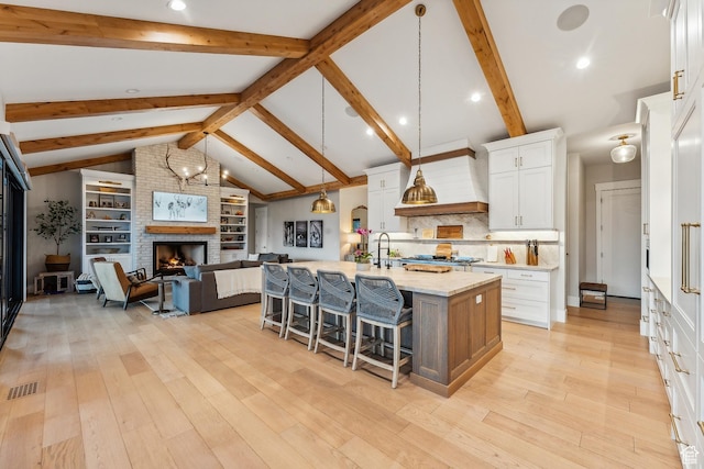 3300 E Hunters Ridge Cir, Heber City, UT 84032 - kitchen featuring a breakfast bar area, open floor plan, custom exhaust hood, white cabinetry, and a kitchen island with sink