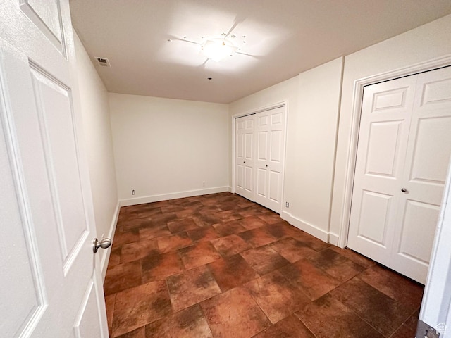 48 W Broadway Unit 2505N, Salt Lake City, UT 84101 - unfurnished bedroom featuring multiple closets, stone finish flooring, and baseboards