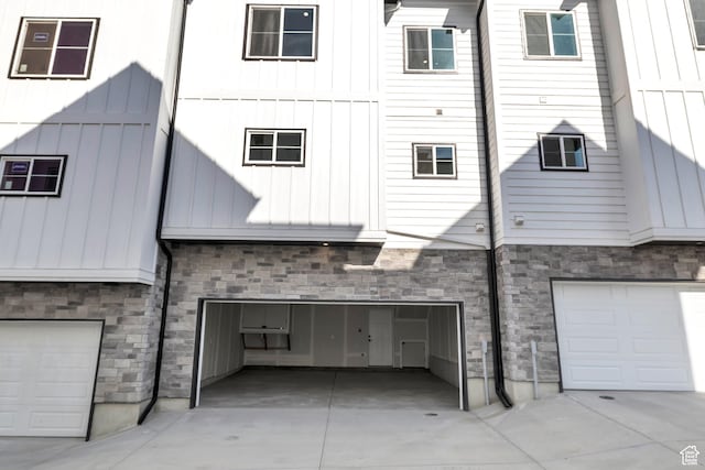 7901 S 2700 E Unit 203, South Weber, UT 84405 - rear view of property featuring a garage, stone siding, concrete driveway, and board and batten siding