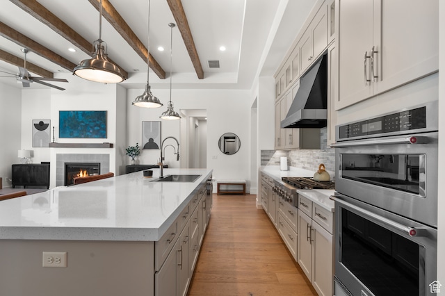 kitchen with a large island, pendant lighting, sink, and beam ceiling