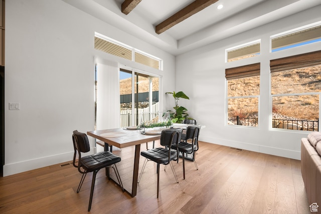 dining space with light hardwood / wood-style flooring and beam ceiling
