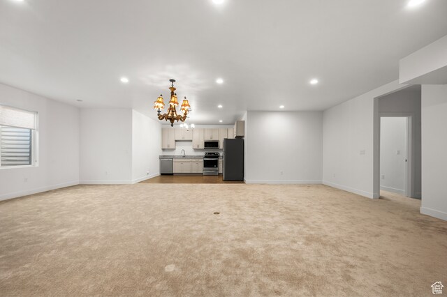 unfurnished living room featuring light carpet, sink, and an inviting chandelier