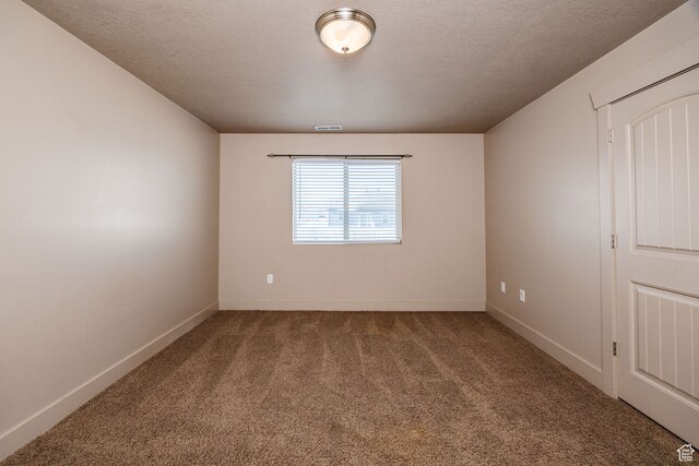carpeted empty room featuring a textured ceiling