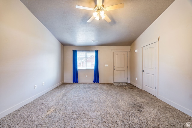 spare room featuring carpet flooring, a textured ceiling, vaulted ceiling, and ceiling fan