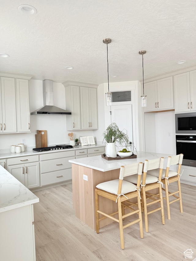 577 N Hawthorn Dr Unit 29, Salem, UT 84653 - kitchen with wall chimney range hood, stainless steel appliances, light wood-style flooring, a textured ceiling, and pendant lighting