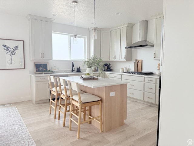 577 N Hawthorn Dr Unit 29, Salem, UT 84653 - kitchen with wall chimney exhaust hood, a sink, light wood-type flooring, a kitchen island, and a textured ceiling