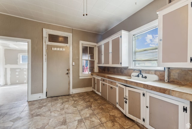 7865 S Main St, Midvale, UT 84047 - kitchen with backsplash, sink, tile counters, light tile patterned flooring, and white cabinetry