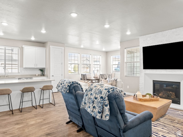 2424 N Lazy J Ln, Lehi, UT 84043 - living room with a textured ceiling, a large fireplace, sink, and light hardwood / wood-style flooring