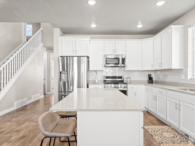 2424 N Lazy J Ln, Lehi, UT 84043 - kitchen featuring white cabinets, light wood-type flooring, a kitchen island, light stone counters, and stainless steel appliances