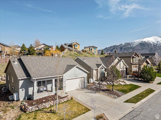 view of front of property featuring an attached garage, a residential view, driveway, and stucco siding