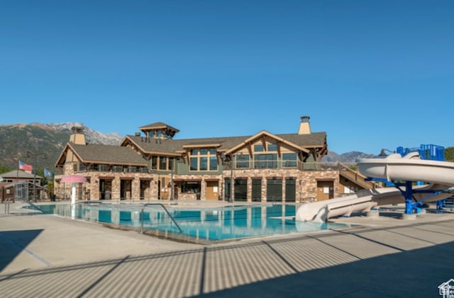 pool featuring a patio, a mountain view, and a water slide